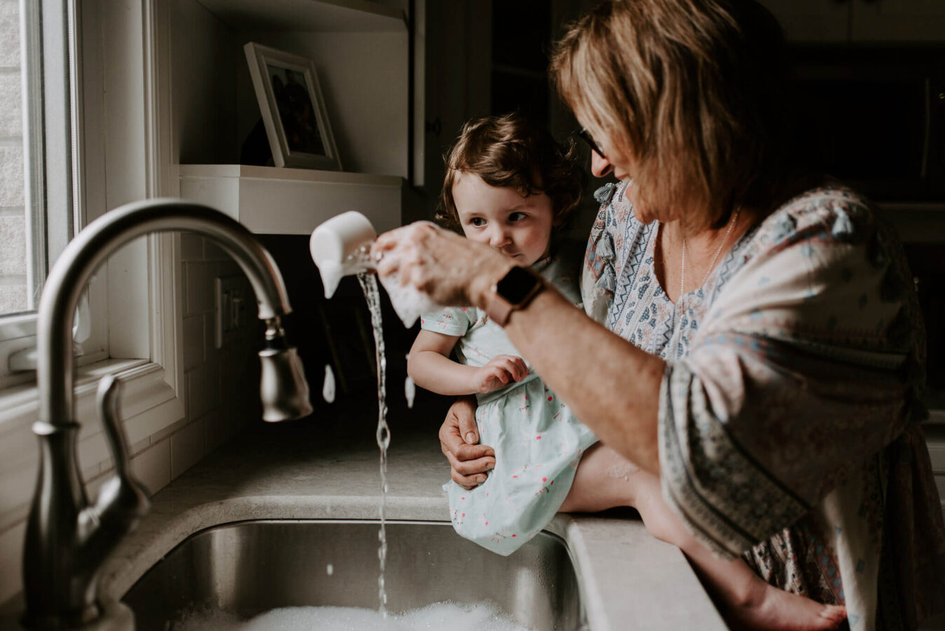 Young girl playing with bubbles in the kitchen sink during a family photoshoot