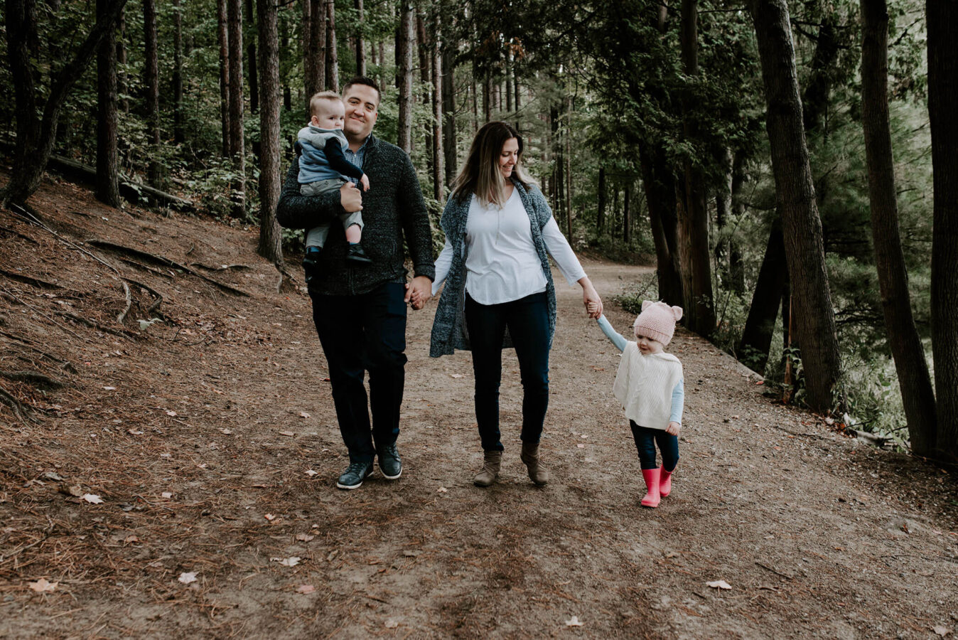 A family of four walking during a family photo session in a forest