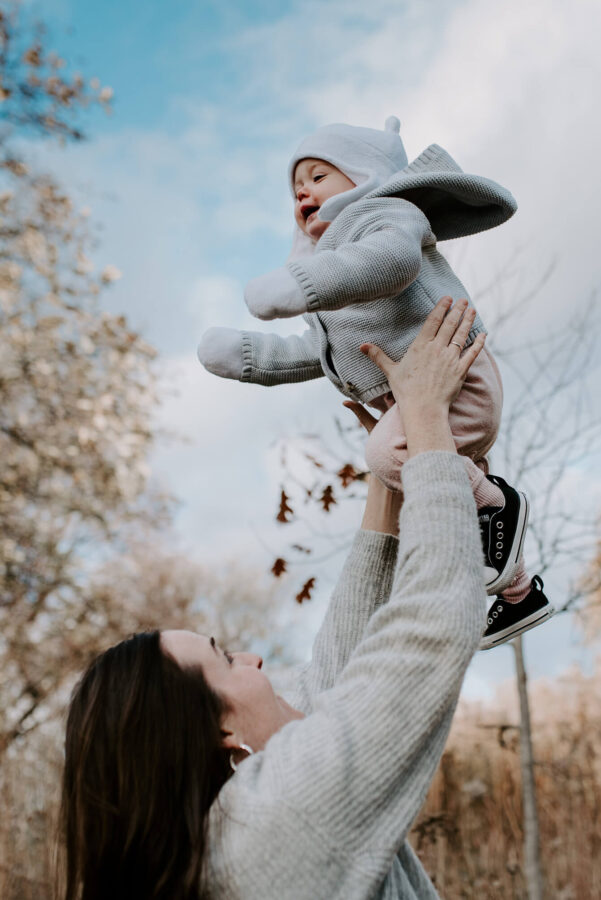 Mom playfully throwing baby girl up in the air