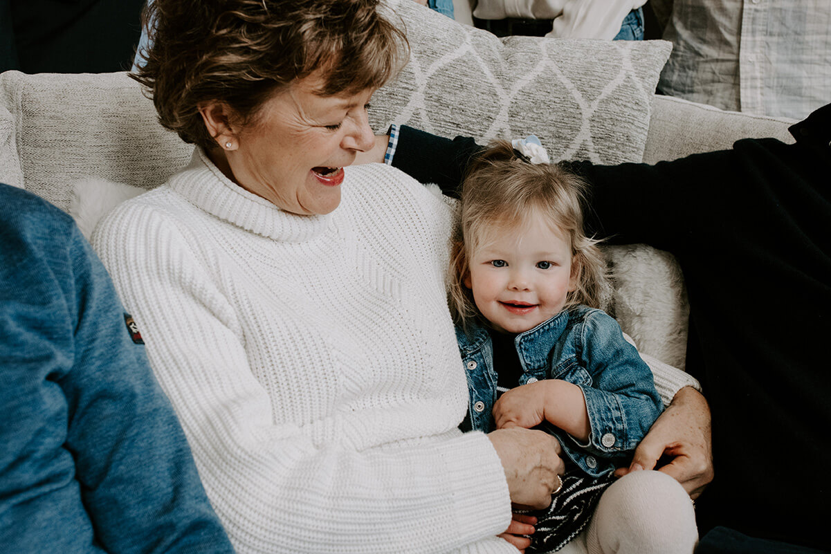 Grandma and granddaughter sitting together on a couch during a family photoshoot